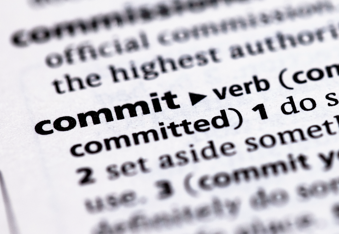 Close-up of a dictionary page highlighting the word "commit" with its pronunciation and definition.