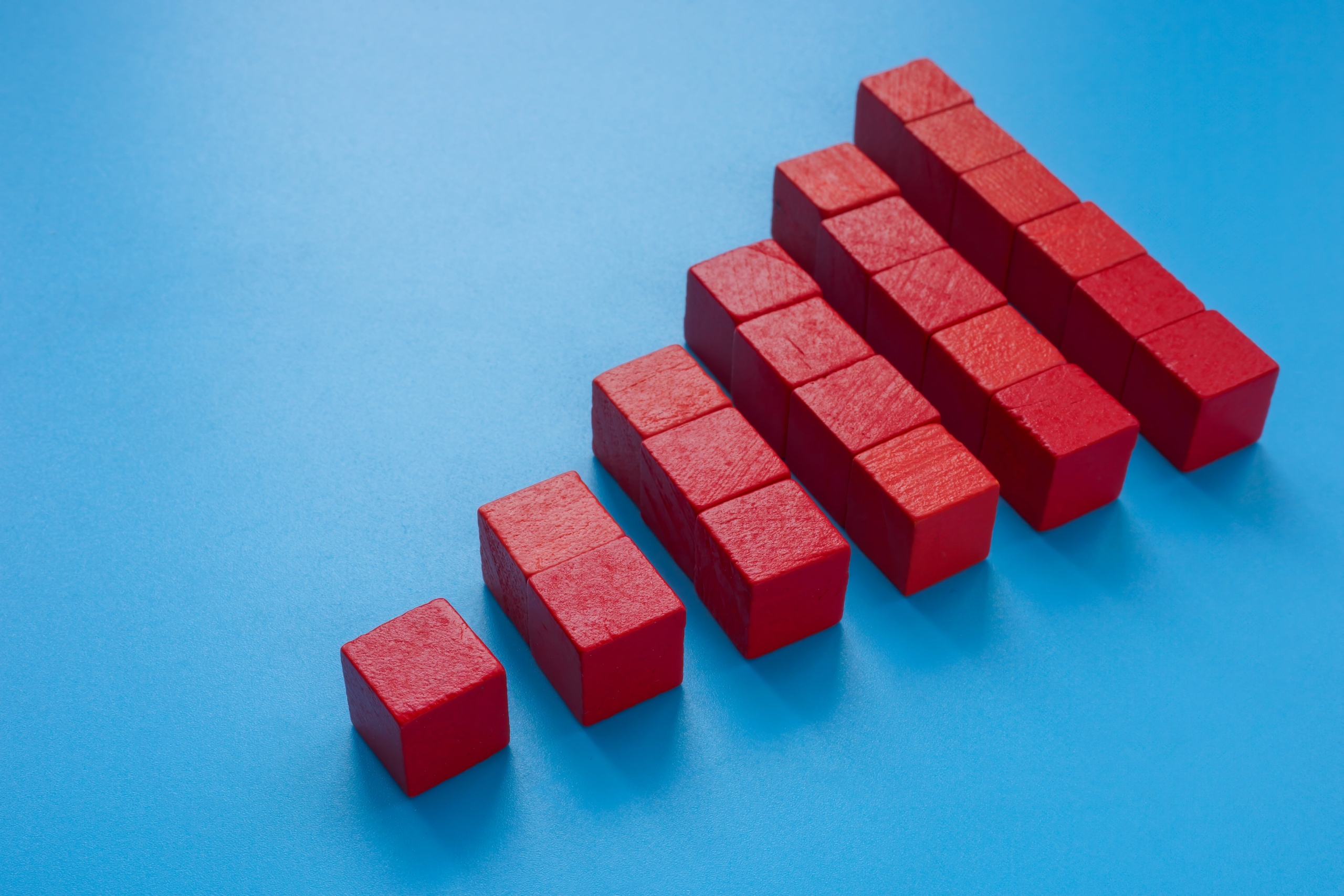 Red cubes arranged in ascending order on a blue background, forming a bar graph-like shape.