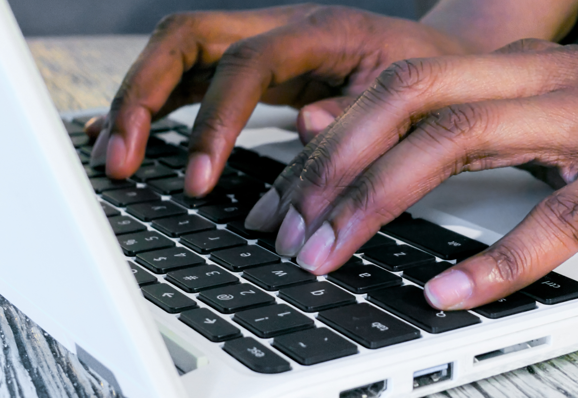 Hands typing on a black keyboard of a laptop, focusing on the keys and fingers.