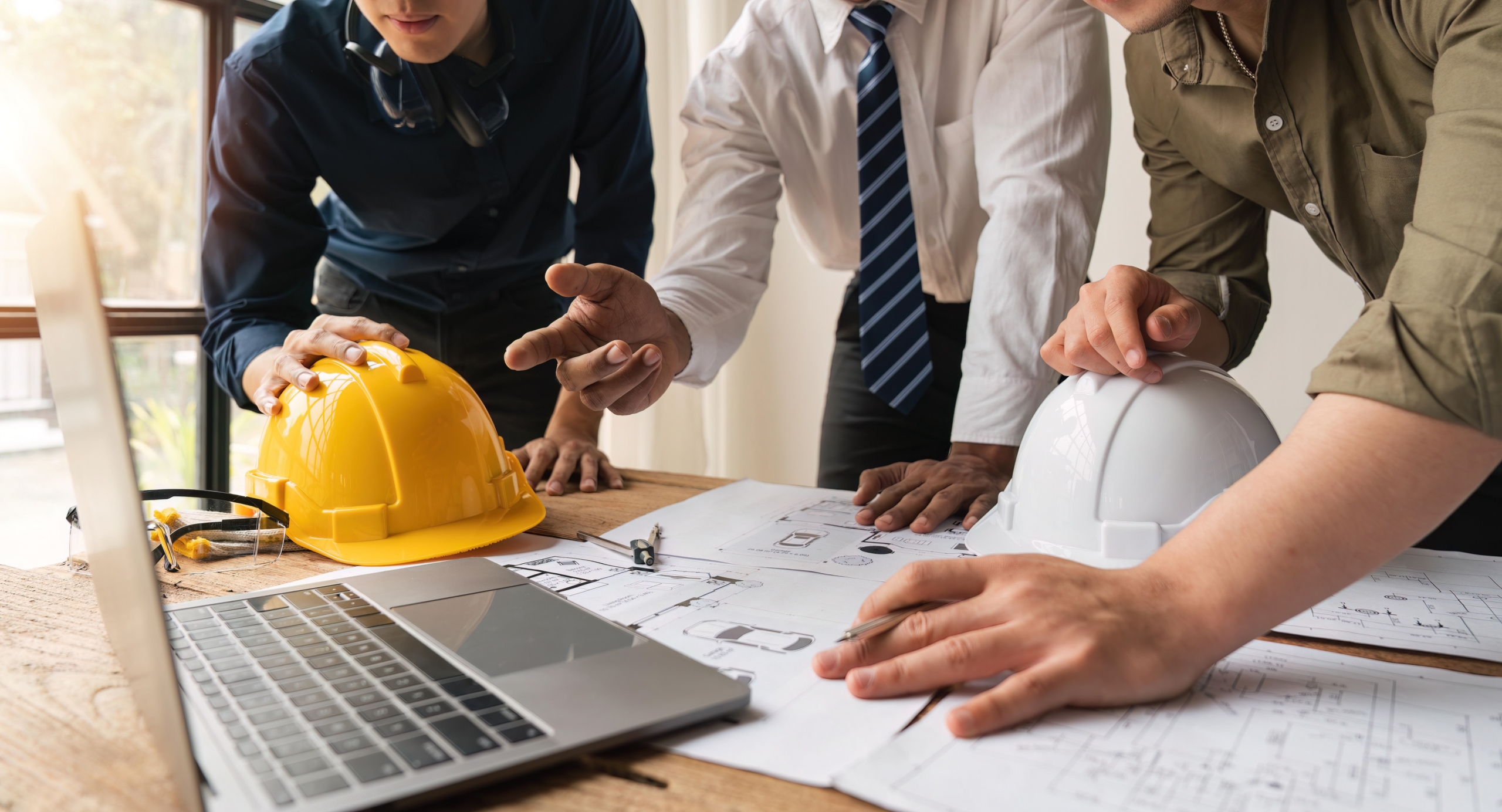 Engineers discuss architectural plans and blueprints for a building project during a team meeting.
