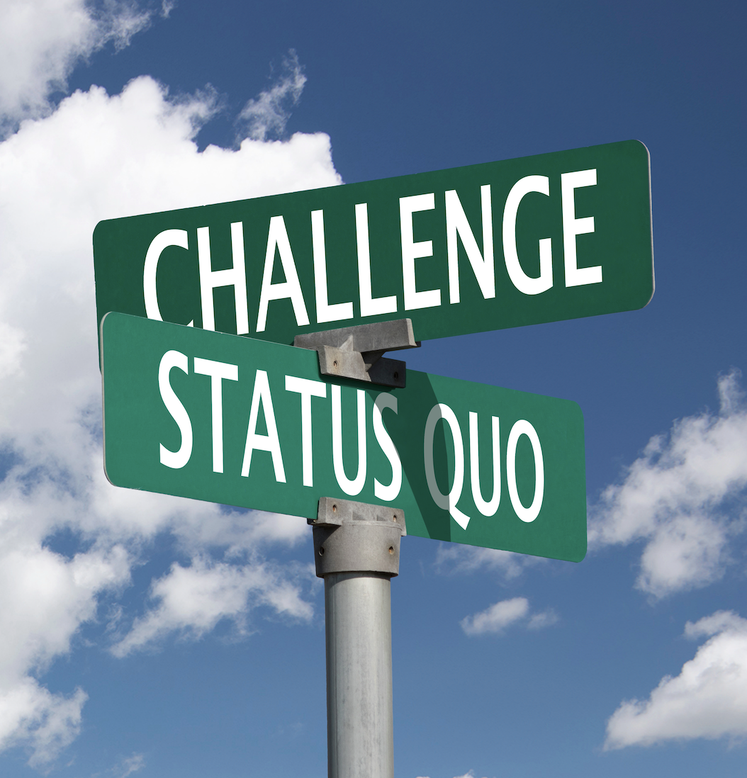 Street signs reading "Challenge" and "Status Quo" against a blue sky with clouds.